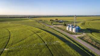 Aerial view of corn field with sprinkler, grain bins, and farm buildings. | Photo 122849023 © Marek Uliasz | Dreamstime.com