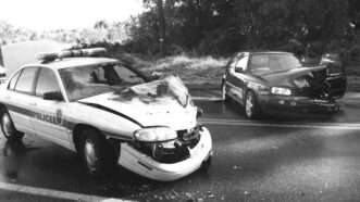 Black-and-white image of a car accident involving a dark sedan and a police car, each with extensive front-end damage. | Thomas Carter | Dreamstime.com